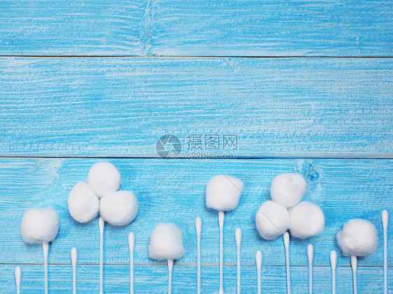 白色吸收棉花球和木制蓝底的棉花芽作为图片