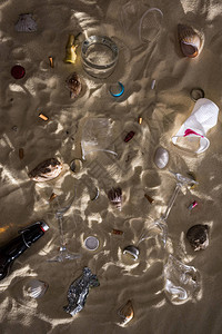贝壳玻璃瓶散落的烟头碎玻璃苹果核塑料杯和糖果包装纸的顶视图背景图片