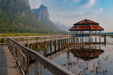 LotusLake是泰国日落时的旅游地点晚上在湖中的木道上图片