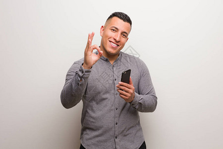 年轻拉丁男子拿着电话欢乐和自信的安心图片