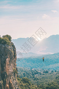 一个人正沿着一条拉长的吊索行走山中的高线人抓住平衡走钢丝者在大自然中的表现Highliner图片