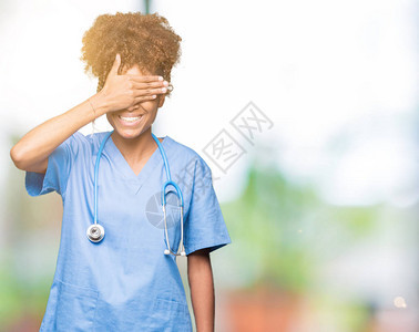 年轻的非洲裔美国医生女人在与世隔绝的背景下微笑着用手捂着眼睛大笑图片
