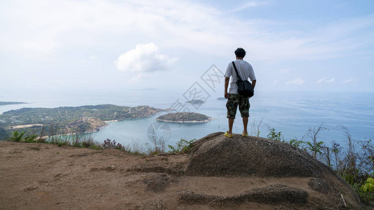 独自一人的男摄影师或旅行者站在泰国普吉岛的岩山上思考一些东西图片