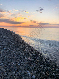 海河湖池塘和热带温暖度假胜地岩石海滩上美丽的黄光日落图片