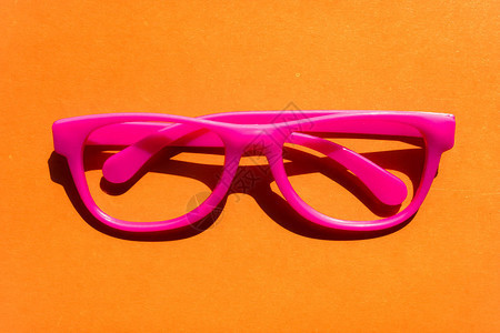 橙色背景的粉红色塑料眼镜眼镜或眼镜有图片
