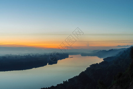 从河上的高岸查看大雾下有森林的河岸黎明倒映在水中在风景如画的黎明前天空中的黄色条纹五颜六色的平静的早晨大气景图片