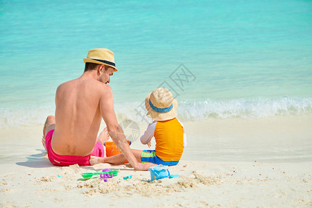 三岁的小孩男和父亲一起在海滩上度假在马尔代夫图片
