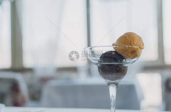 两勺冰淇淋芒果和巧克力在一个温馨的餐厅背景下一个清图片