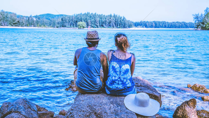 亚洲情人女和男人旅行自然旅行放松在海边的岩石上图片