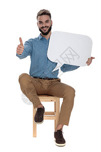 穿着蓝色牛仔裤衬衫的坐着的商人在白色背景上举着谈话标志时表图片