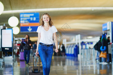 携带行李在国际机场行走的年轻女子为图片