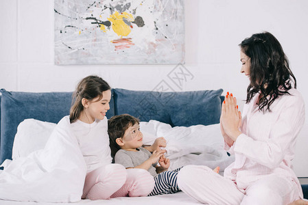 快乐的母亲在卧室里带着可爱的女儿和子在喜悦的小孩图片