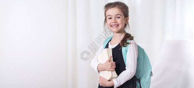 女小学生背着包和浅色背景的书教育和小学的概念图片