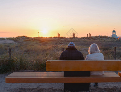 年老夫妇男女在夏天日落时坐在大图片
