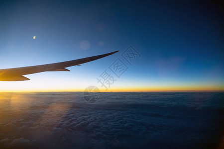 空中飞机翼飞越云层的景象和日出时飞过陆地自然和旅行概图片