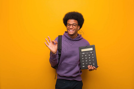 年轻非洲美国学生男子拿着计算器图片