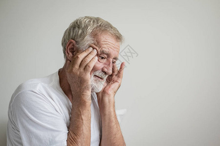 高年男子在白房的床上独自思考或图片