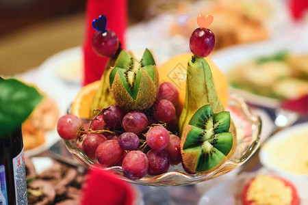餐厅桌子上放着新鲜葡萄猕猴桃和梨的水果盘图片