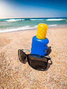 沙滩上的太阳镜和防晒油的近照图片