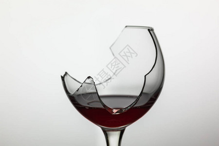 破碎的酒杯与白色背景上的红酒图片