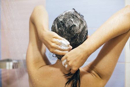 年轻快乐的女人用洗发水洗头图片