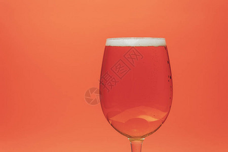 珊瑚橙背景上的玻璃啤酒背景图片