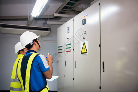 电气工程师在控制室和记录生产过程中工厂的电力运行情况背景图片