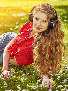 听耳机的女孩在绿草上捕捉节奏音乐图片