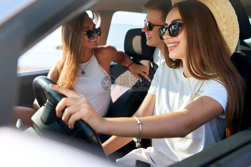 旅行的生活方式朋友们租了一辆车去进行夏季公路旅行戴眼镜和草帽的女司机很开心女人学会了汽车驾驶并获得了执照图片