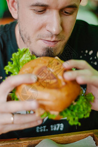 餐馆里的人吃汉堡包他饿了吃着好吃的口背景图片