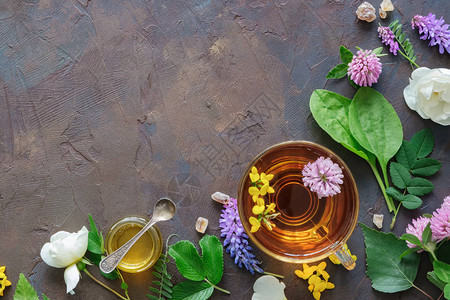 健康凉茶药材和小蜂蜜罐的玻璃杯图片