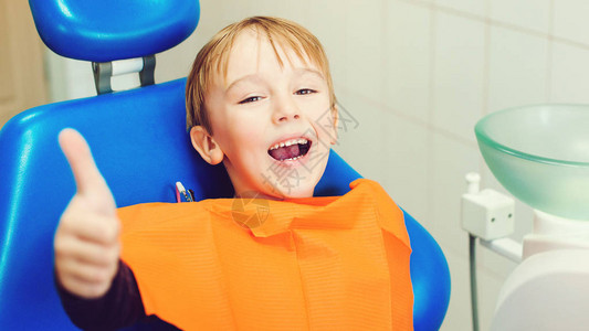牙医在诊所检查小男孩的牙齿快乐的男孩坐在牙科椅上孩子在牙医治疗背景图片