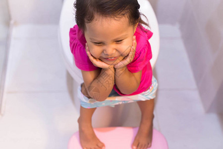 一个小女孩坐在一个白色浴室的大马桶上图片