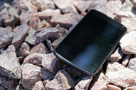 破碎的手机被遗弃并丢失在砾石中图片