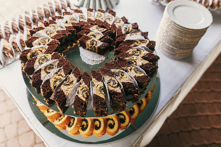 白色和巧克力甜点配奶油蛋糕片放在架子上现代甜桌在婚礼或婴儿送礼会上图片