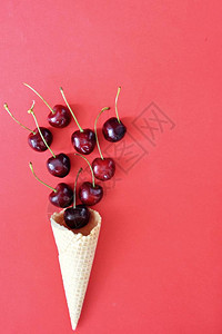 冰淇淋圆锥在多彩背景的前面充满樱桃作为夏天水果新鲜图片