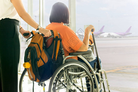 母亲坐在轮椅上等待在国际机场登机的图片