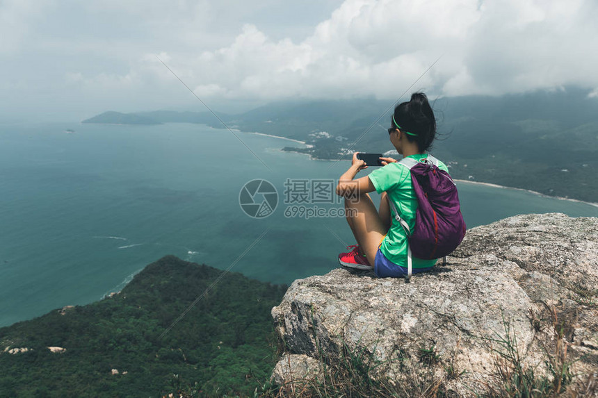 在海边山顶与智能手机拍摄成功妇女希克Hiside图片