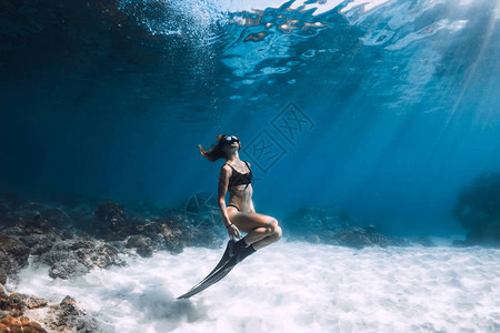 女自由潜水者在沙海上摆着有鳍的鱼翅图片