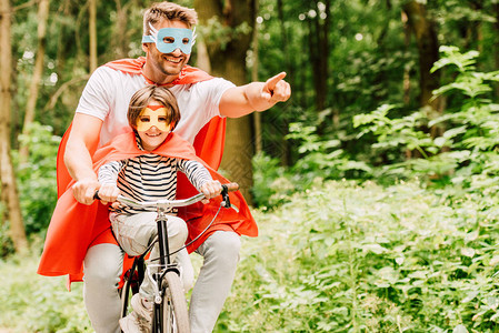 父亲和孩子骑自行车在森林周围骑自行车穿着图片