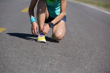 女子赛跑者在小路上系鞋带图片
