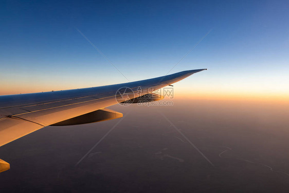 飞机翼在城市上空飞机在蓝天上飞行从飞机窗口的风景早上有阳光的商业航空公司飞行云层之上的平面机翼图片