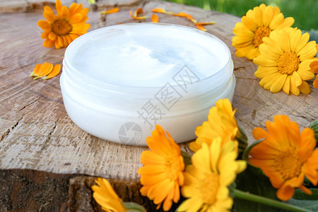 一罐白化妆品奶油用于身体护理木上鲜橙色圆筒花背景图片
