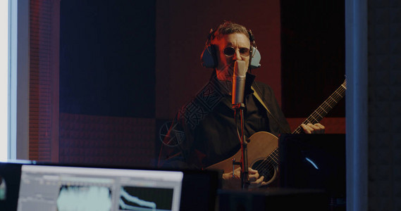 录音师在录音室录制吉他手的中景背景图片