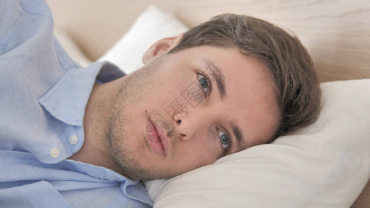 思考的年轻人侧躺在床上的特写背景图片