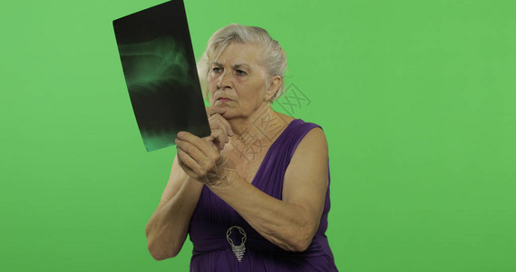 一位老妇人正在检查她的X射线图像一件紫色礼服的老俏丽的祖母放置您的徽标或文本色度图片
