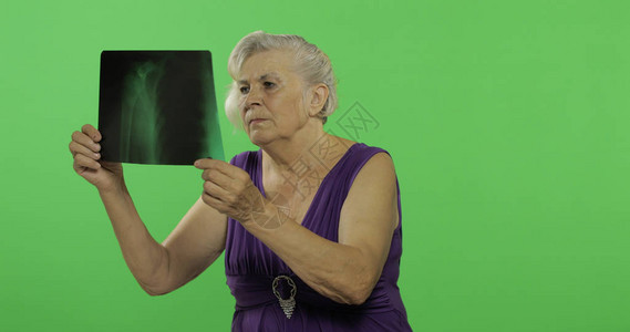 一位老妇人正在检查她的X射线图像一件紫色礼服的老俏丽的祖母放置您的徽标或文本色度图片