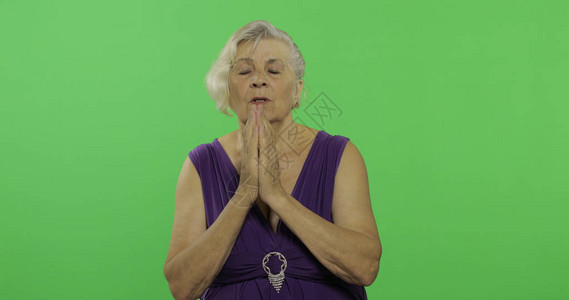 一位年长的女士双手合在一起祷告老漂亮的祖母穿着紫色礼服您可以进入标志或文字处按下克罗马图片