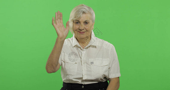 一位老年妇女手挥着相机和微笑图片
