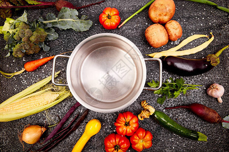 黑背景的空烹饪锅周围的各种有机蔬菜成分顶端图片